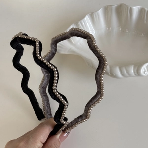Close-up of pearl embellished velvet wavy headbands in black and dark grey colors