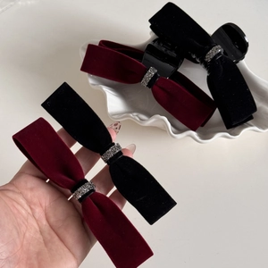 Velvet bow hair clips in black and burgundy with rhinestone accents on a shell tray