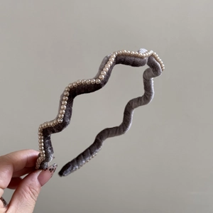 Detail of wavy grey velvet headband decorated with elegant white faux pearls