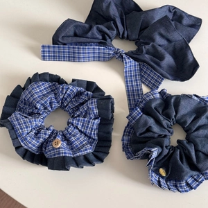 Close-up of three blue denim and plaid scrunchies with wood and gold button details