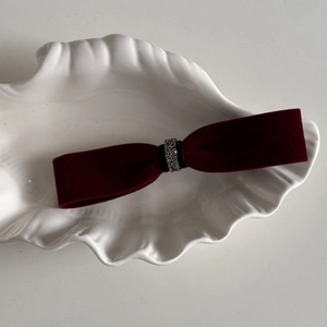 Detailed close-up of dark red velvet bow hair clip with silver rhinestone embellishments