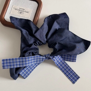 Detail of dark blue denim scrunchie with blue-white plaid bow on a vintage wooden tray