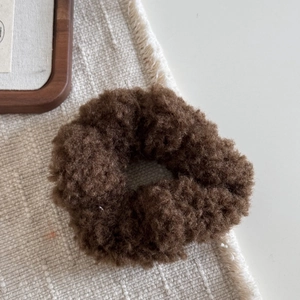 Détail du chouchou en peluche marron foncé avec texture douce en laine pour l'hiver