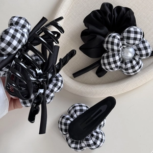 Close-up of black and white checkered flower hair clip set with pearl detail