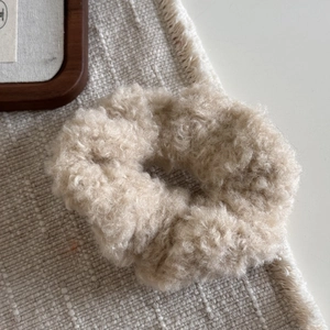 Détail de la texture d'un chouchou en peluche crème sur un tapis tissé avec polaire