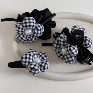 Detail of checkered flower hair accessories set with pearls on beige tray background