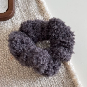 Détail du chouchou en peluche gris foncé avec texture laine d'agneau douce pour coiffure d'hiver