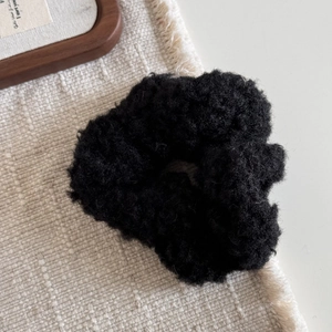 Détail du chouchou en peluche noire avec une texture douce en faux mouton bouclé