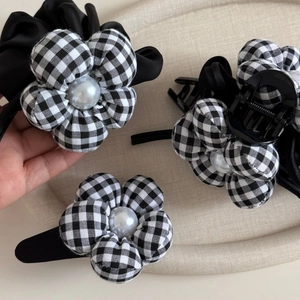 Elegant black and white plaid flower hair accessories set with pearls on a beige tray
