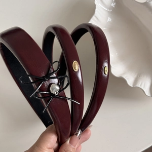 Macro detail of three burgundy leather headbands with metallic heart and oval charms