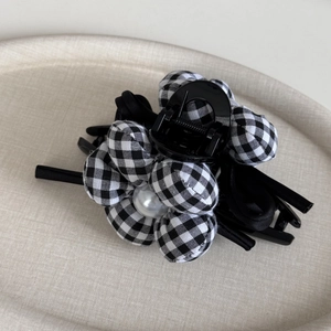 Detail of checkered fabric flower hair claw clip with large pearl and silk bow decoration