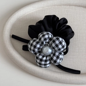 Close-up of black and white plaid flower hair clip with a grey pearl detail and ribbons