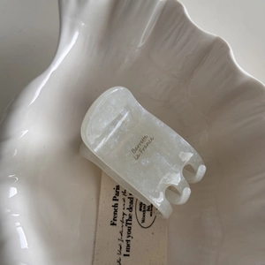 Detail of pearl white acetate hair claw clip with French text on a vintage tray