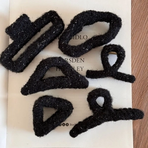 Detailed macro view of black plush hair claws with shimmering silver threads in five shapes