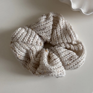 Detail view of cream knit scrunchie with soft textured yarn and colorful flecks