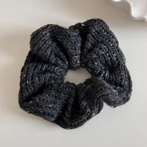 Close-up of thick knitted dark grey wool scrunchie with subtle speckled texture