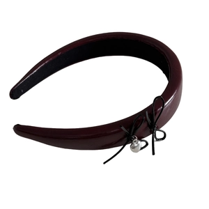 Vintage burgundy leather headband with heart charm and bows on a white background