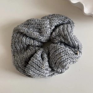 Detailed texture of gray knit scrunchie with colorful tweed dots and thick wave pleats