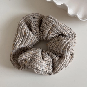 Close-up of oatmeal knit scrunchie with colorful speckles and soft wool texture