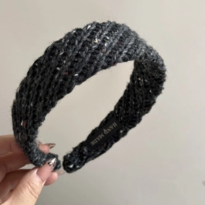 Detailed macro view of dark grey knitted headband with colorful tweed specks and handmade label