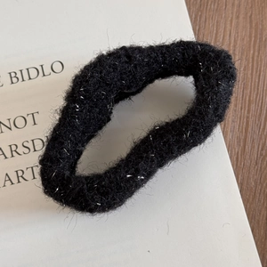 Close-up of black plush hair claw clip with silver glitter threads and soft texture