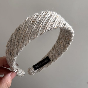 Detail of cream knit headband showing woven texture and handmade textile label