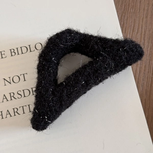 Detail of black fuzzy hair claw clip with silver glitter threads on a book background