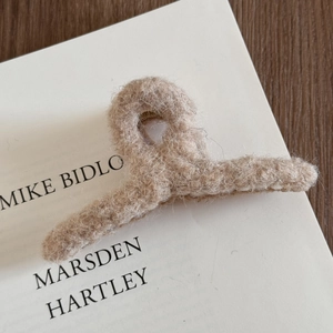 Gros plan d'une pince à cheveux en peluche beige doux pour femme sur une page de livre