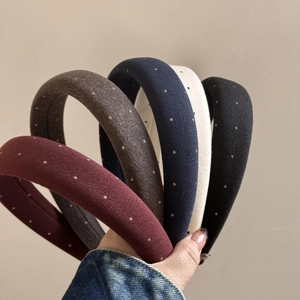 Detailed view of padded polka dot headbands in various vintage colors held by a hand