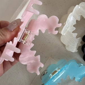 Detail showing wavy marble texture acrylic hair claws in pink, blue, white, and black colors