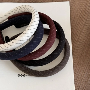 Détail de cinq serre-têtes en tissu à rayures vintage en marine, rouge, noir et marron