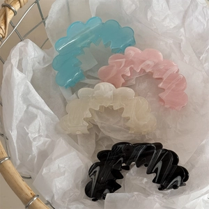 Close-up of four wavy cloud-shaped hair claw clips in marble and solid pastel finishes