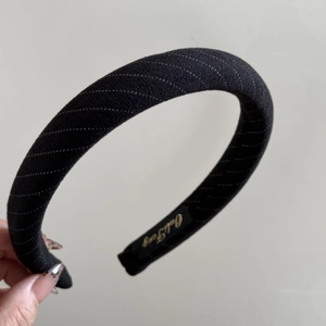 Détail d'un serre-tête rembourré en tissu noir à rayures avec étiquette de marque interne