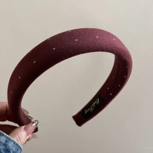 Close-up of burgundy polka dot sponge headband showing fabric texture and inner brand label