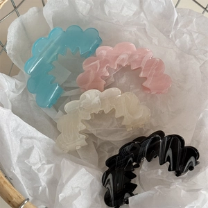 Detail of wavy acetate hair claws in pastel blue, pink, cream, and marble patterns