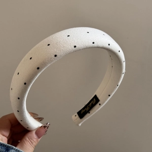 Detailed macro view of the padded white headband with black polka dots and interior brand label