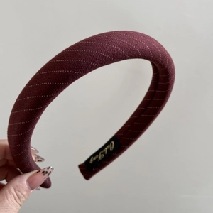 Gros plan du serre-tête en tissu bordeaux à rayures avec étiquette de marque