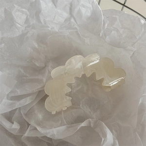 Detailed macro view of cream wavy hair claw clip with elegant marble resin texture