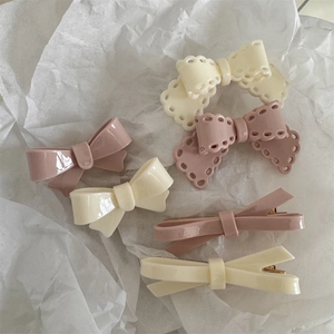 Detail of cream and pink bow hair clips set on textured white paper background