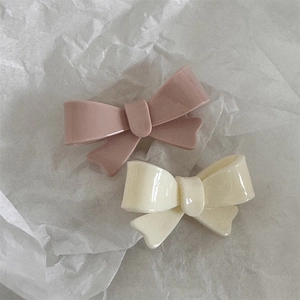 Detail view of pink and cream bow hair clips on textured white paper background