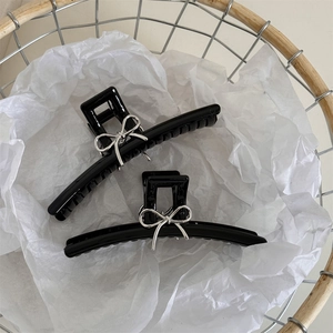 Dettaglio di fermagli per capelli neri con eleganti fiocchi in metallo argento nel cesto