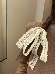 Detail of elegant lace bow hair tie with pearl accent styled in a braided updo