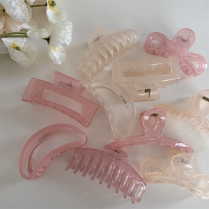 Détail de diverses pinces à cheveux rose et abricot sur un fond blanc avec fleurs
