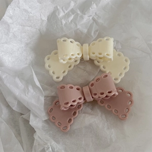Close-up of cream white and soft pink bow hair clips with delicate hollow lace edges