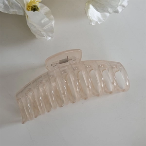 Gros plan d'une grande pince à cheveux rose translucide avec finition brillante et ressort