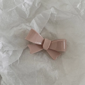 Detailed close-up of pink bow hair clip with high-gloss finish on white paper