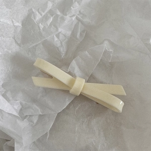 Close-up of cream velvet bow hair clip with layered design on textured background