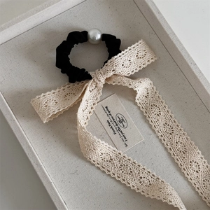 Close-up of elegant lace bow hair claw with velvet and pearl detail on a display tray