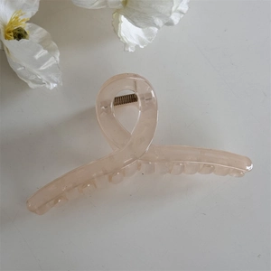Détail macro d'une grande pince à cheveux rose pastel effet gelée avec ressort métal