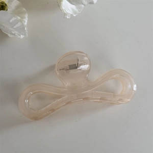 Détail du ressort en métal sur une pince à cheveux transparente de couleur champagne